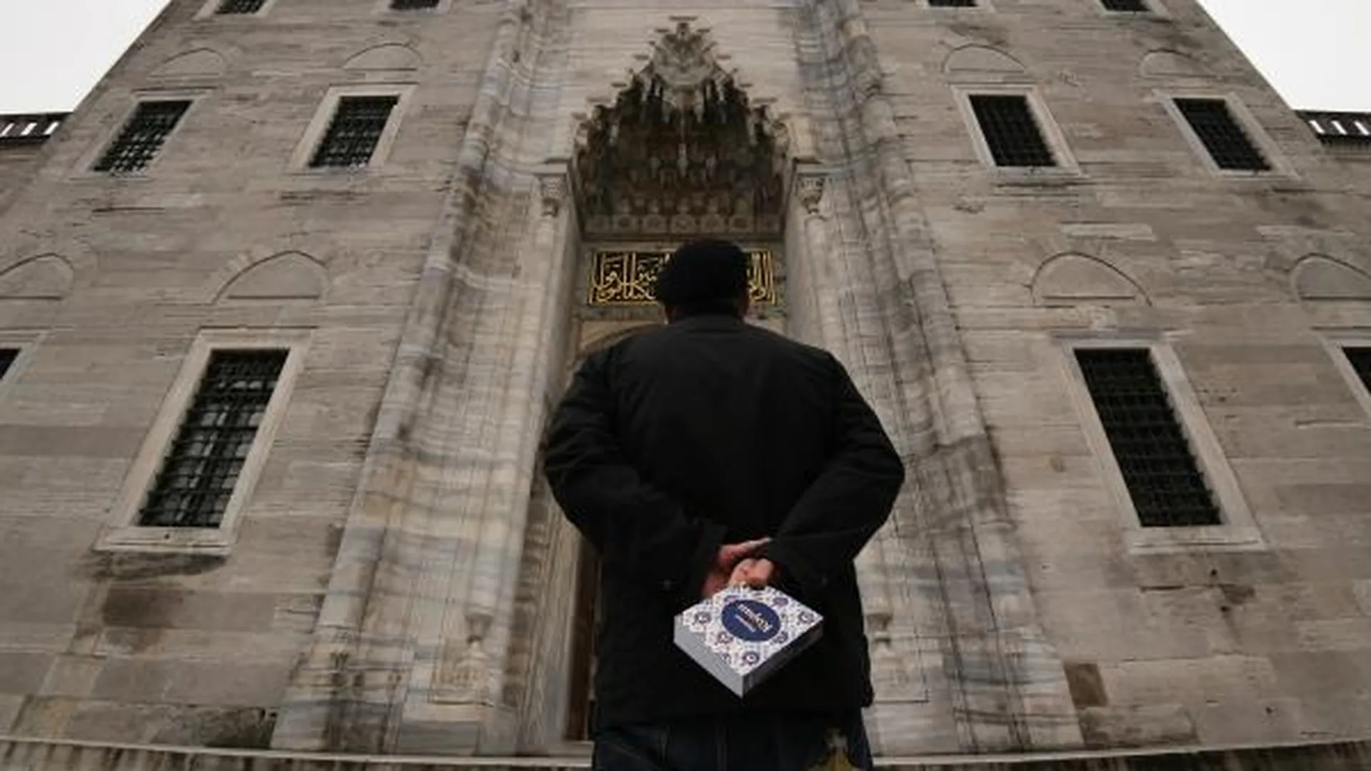 Мужчина стоит у входа в мечеть Сулеймание в Стамбуле