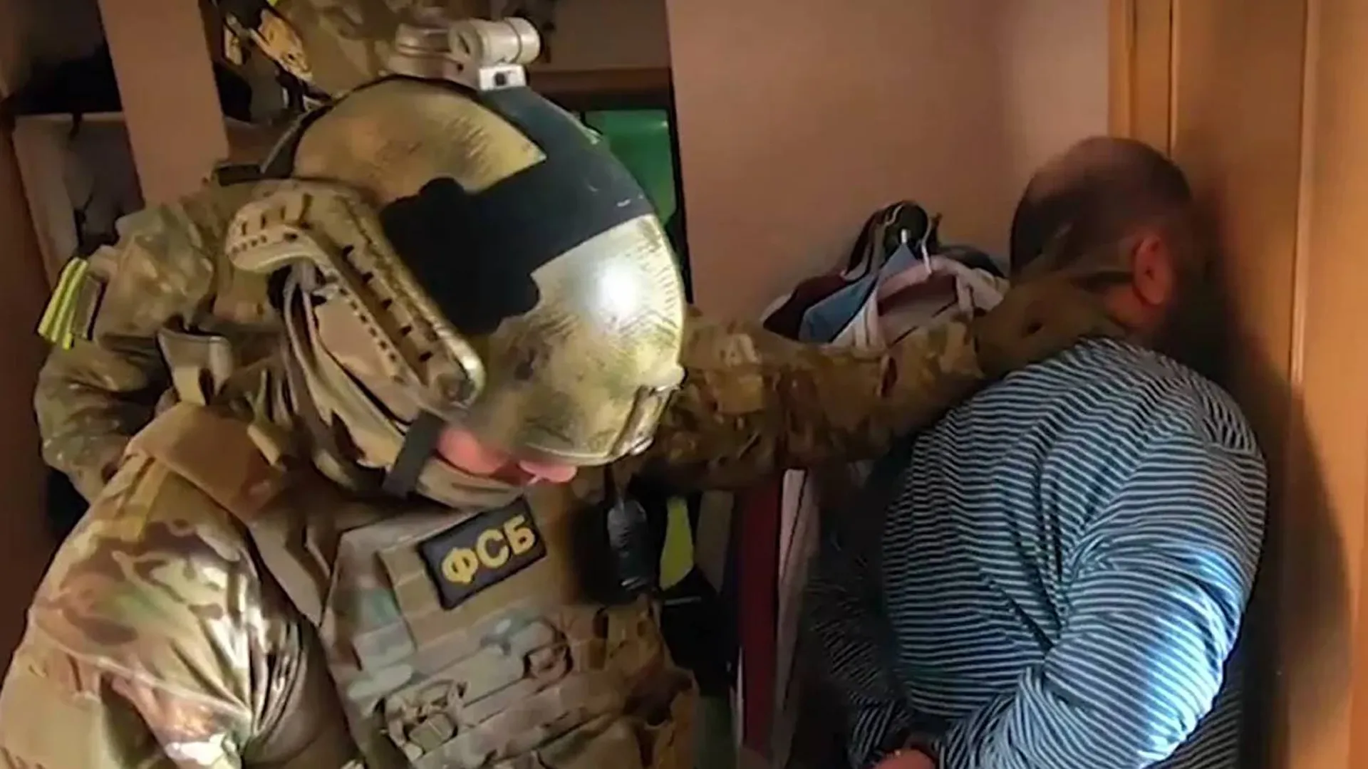 Люди в форме ФСБ задерживают мужчину в квартире